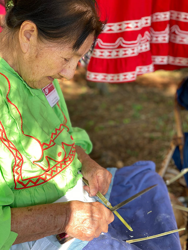 a woman working with a strip of wood or cane